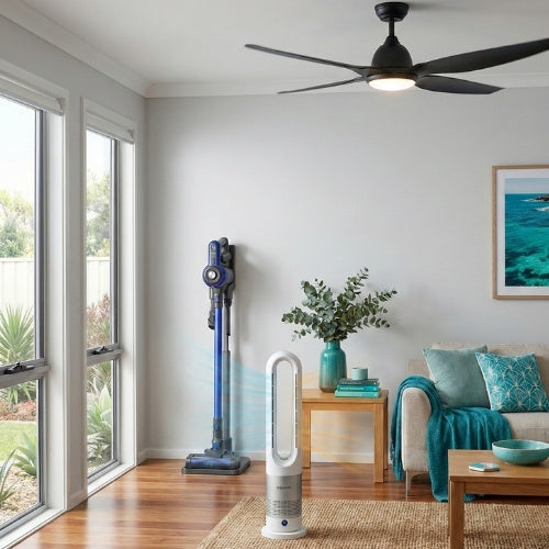 Gemini said Rivercity Furniture living room displaying essential home appliances. A blue stick vacuum, white bladeless fan, and black ceiling fan are integrated into a bright space with coastal teal decor and textiles.